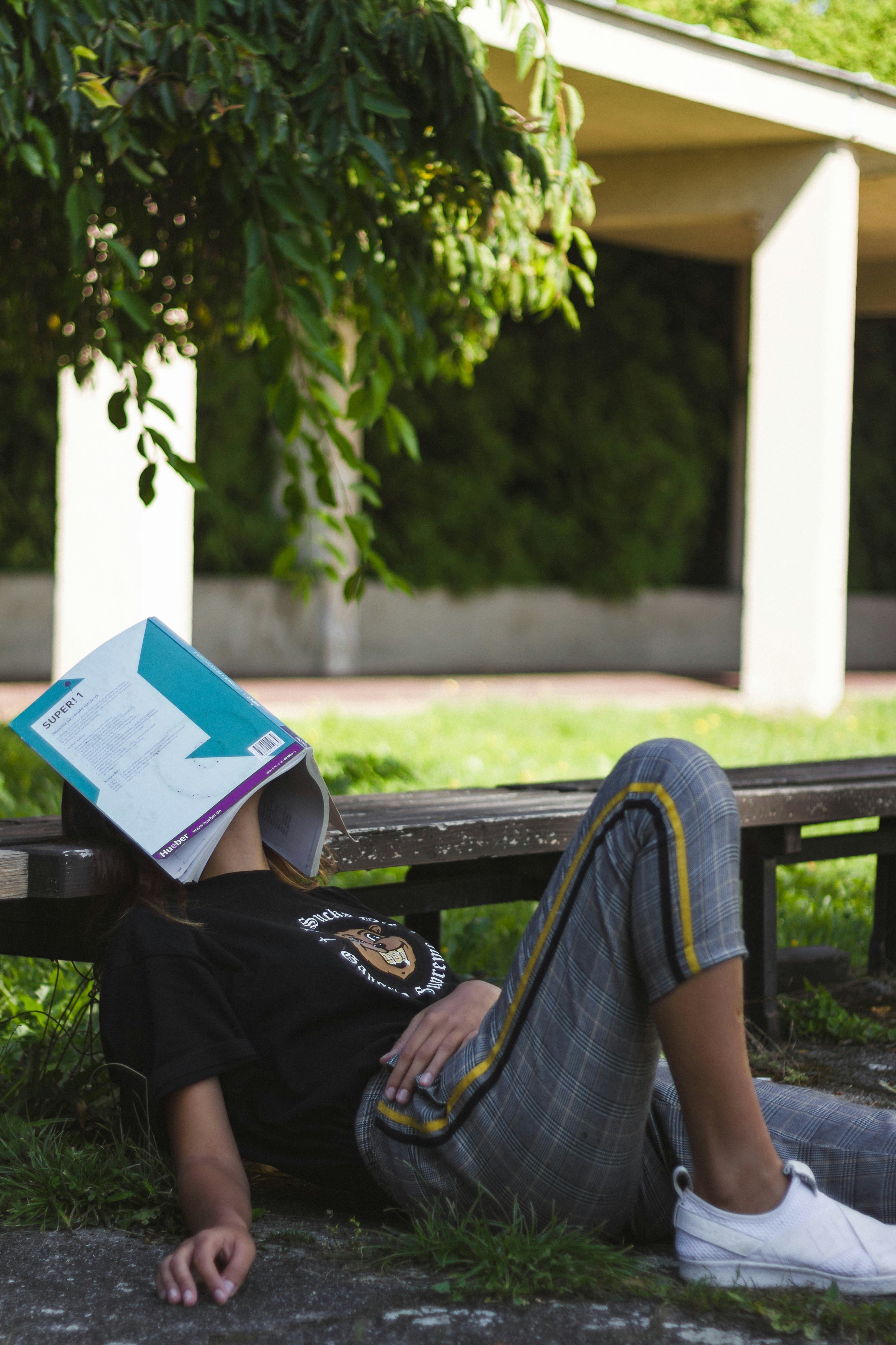 Aspirant resting on a bench with a book over their face — the emotional reality of climbing cut-offs