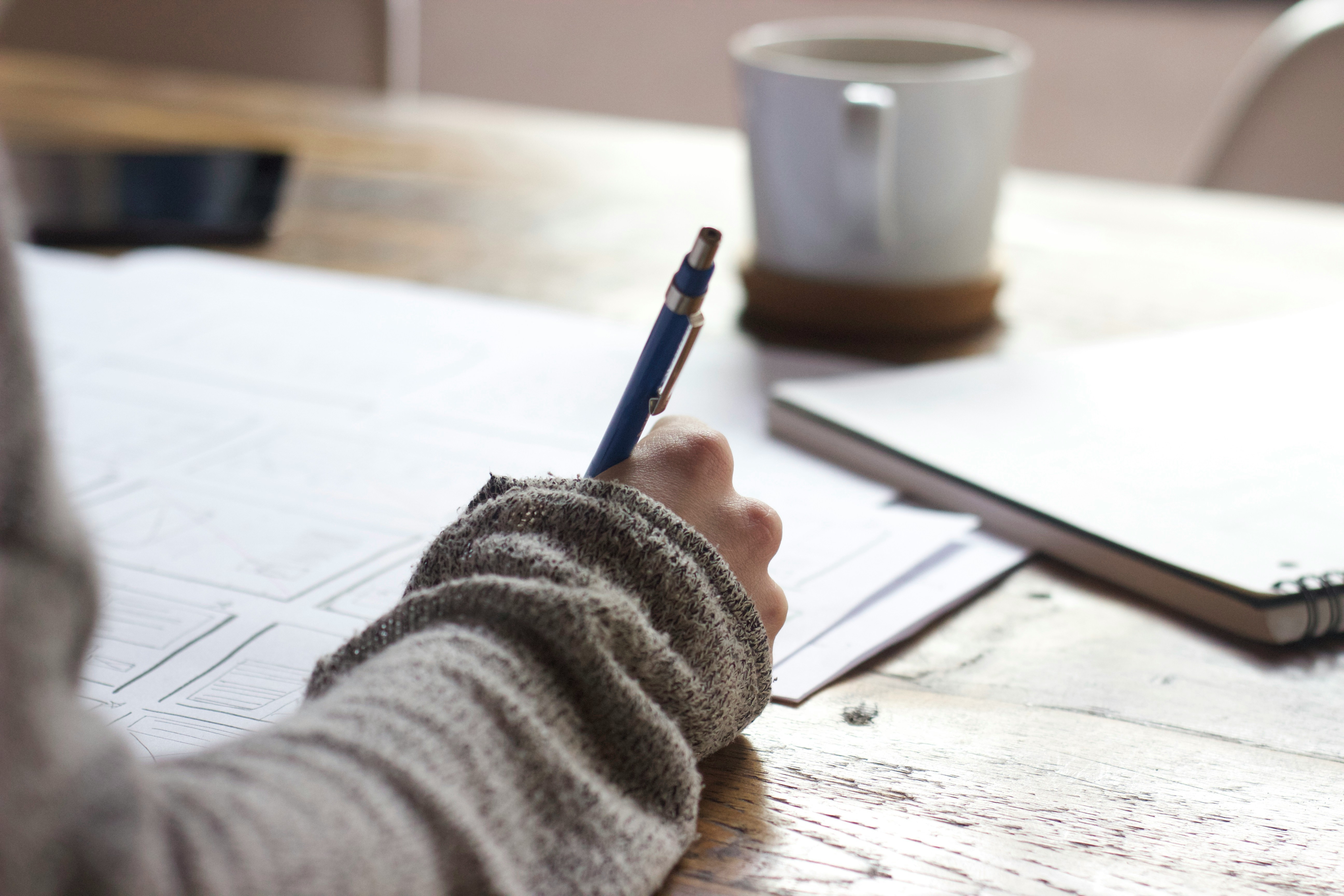 Hand writing in a notebook with a coffee mug — calibrating SSC CGL preparation strategy