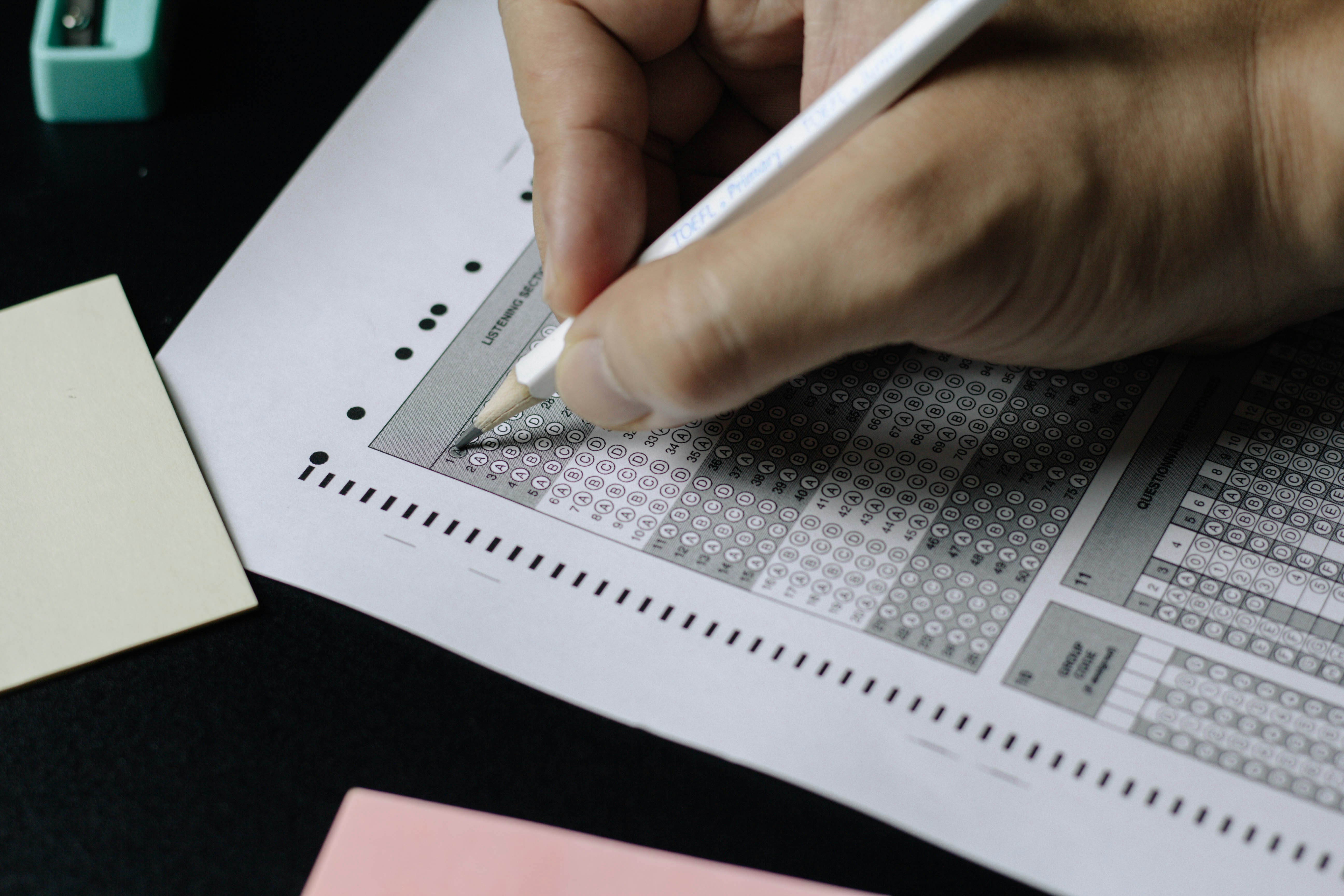 Hand filling a competitive exam OMR answer sheet with a pencil โ banking exam preparation